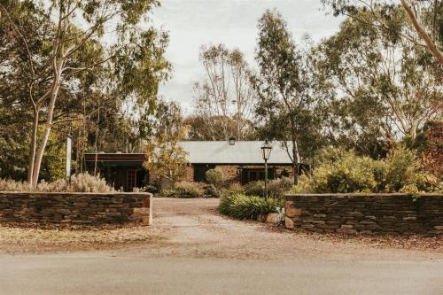 a house with a stone wall and a driveway at Mintaro Cottage in Mintaro