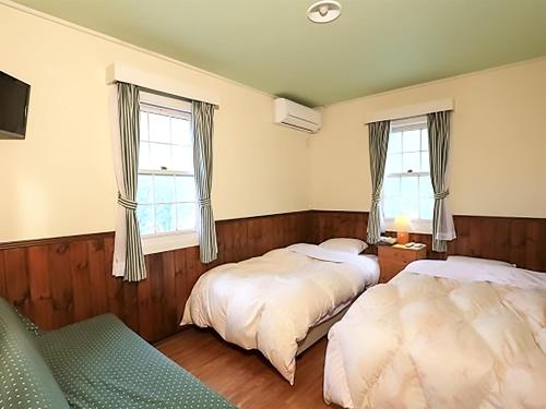 two beds in a room with two windows at Human resort in Yamanakako