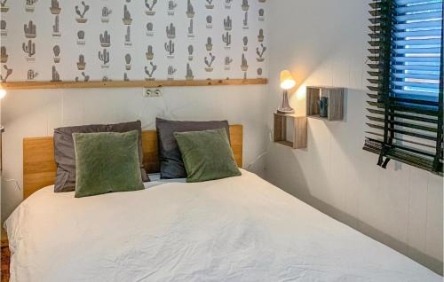 a bedroom with a white bed with two green pillows at Amazing Caravan In Hattemerbroek With Wifi And 1 Bedrooms in Hattemerbroek