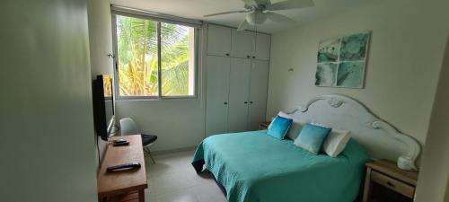 a bedroom with a bed with blue sheets and a window at Pedacito de cielo in Progreso