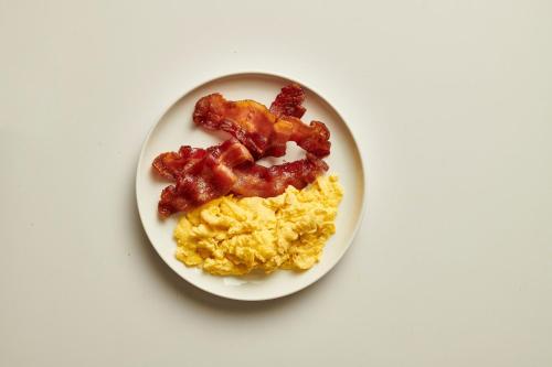 a white plate with scrambled eggs and bacon on it at Holiday Inn Ardmore by IHG in Ardmore