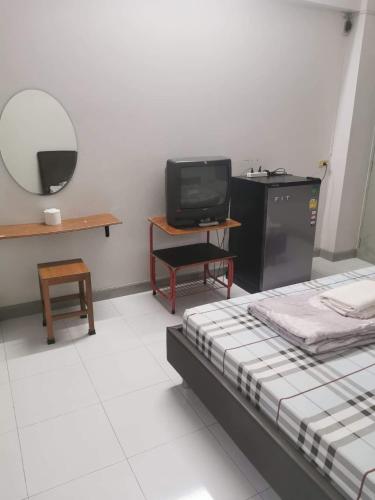 pokój z dwoma łóżkami, telewizorem i stołem w obiekcie Thanya Mansion w mieście Kanchanaburi