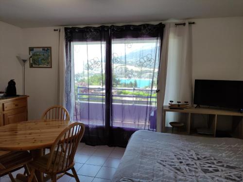 une chambre avec un lit, une table et une fenêtre dans l'établissement Studio vue sur lac et montagne, à Savines