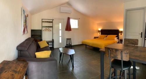 a living room with a bed and a couch at Le Mazet, studio avec terrasse et spa in Saint Alban Auriolles