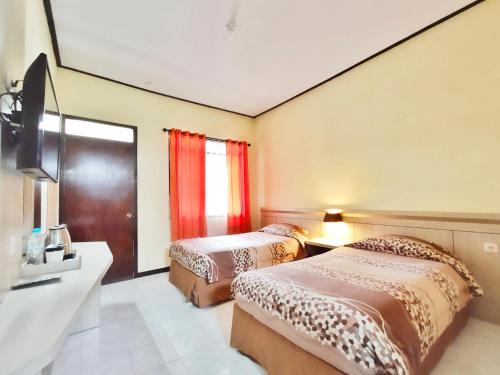 um quarto de hotel com duas camas e uma televisão em Bromo Permai 1 em Bromo