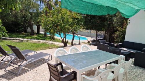 eine Terrasse mit einem Tisch, Stühlen und einem Pool in der Unterkunft House with exclusive pool and garden 7 min walk from the beach and the center in El Campello