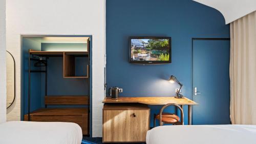 a room with a blue wall with a desk and a mirror at Eden Oak Geelong in Geelong