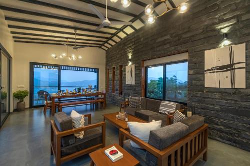 a living room with a stone wall at SaffronStays Ahilya Waters by Kosha Villas, Pawna - pool villa with panoramic view of Pawna Lake in Āmbavna
