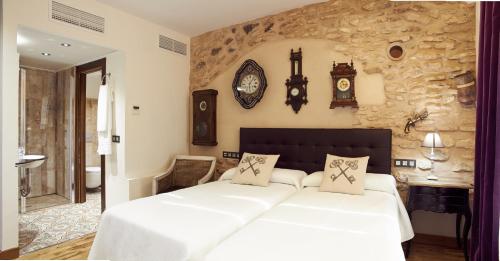 a bedroom with a large bed and clocks on the wall at Hotel Rural Doña Berenguela in Bolaños de Calatrava