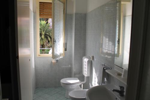 La salle de bains est pourvue de toilettes, d'un lavabo et d'une fenêtre. dans l'établissement Hotel Europa, à Arma di Taggia
