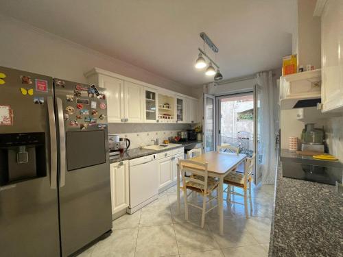 une cuisine avec un réfrigérateur en acier inoxydable et une table dans l'établissement Appartement T4 très bien situé et climatisé, à LʼÎle-Rousse