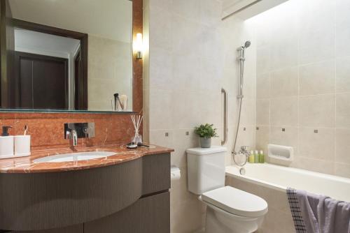 ein Badezimmer mit einem Waschbecken, einem WC und einer Badewanne in der Unterkunft Somerset Bencoolen Singapore in Singapur