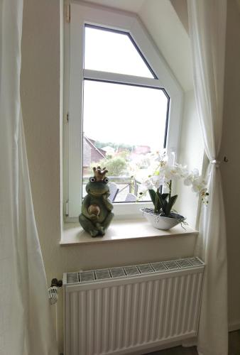 a window with a teddy bear sitting on a window sill at Schaake Hooksiel - Charmante Reetdachwohnung & Kostenfreier Parkplatz in Hooksiel