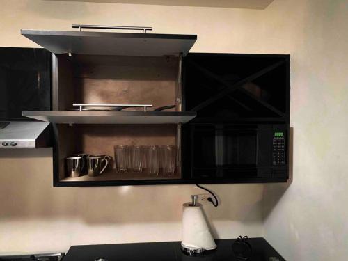 a microwave above a kitchen counter with glasses in it at Casa moderna y elegante en el corazón de Ensenada! in Ensenada