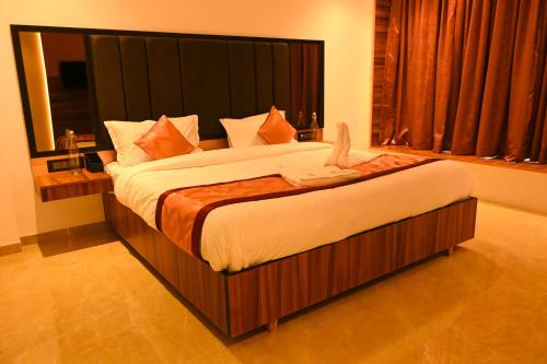 a bedroom with a large bed with a large headboard at Kalki Hotel in Port Blair