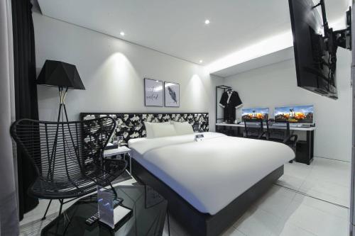 um quarto com uma cama branca e cadeiras pretas em Zam 101 em Busan