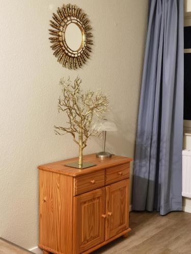 a wooden cabinet with a plant on it with a mirror at Schaake Hooksiel - Charmante Reetdachwohnung & Kostenfreier Parkplatz in Hooksiel