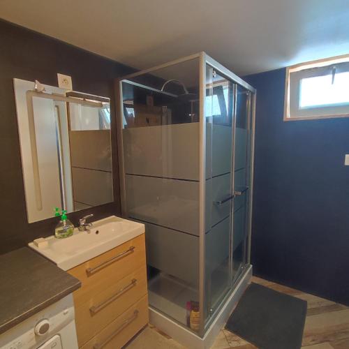 une salle de bain avec une douche en verre et un lavabo dans l'établissement Maison chaleureuse avec parking gratuit sur place, à Coulogne