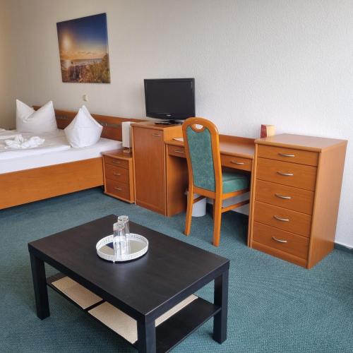 a hotel room with a desk and a bed at Müritz-Pension Waren in Waren