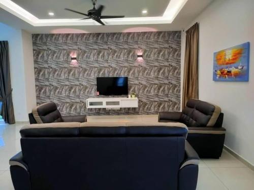 a living room with a couch and a tv on a wall at My Home Kayangan Villa Malacca C10 in Melaka