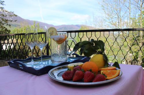 a plate of fruit on a table with wine glasses at Amoroso's house, affittacamere in Caramanico Terme