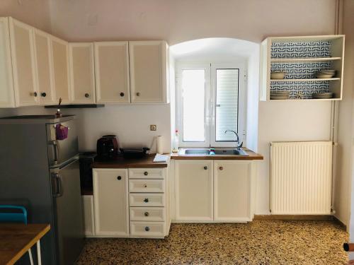 a kitchen with white cabinets and a sink and a window at LaLuzaki in Spetses