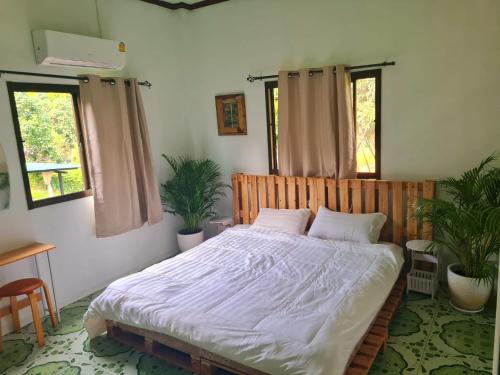 a bedroom with a bed with white sheets and two windows at JENI Homestay โฮมสเตย์หลังใหญ่ปิ้งย่างได้ in Ko Chang