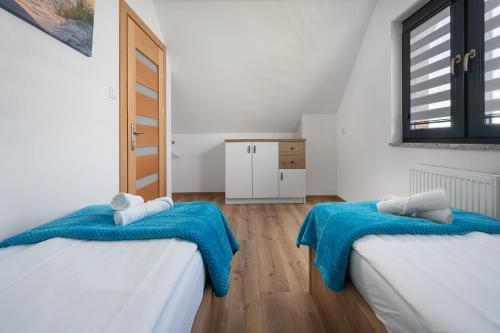 a room with two beds with blue sheets and a window at Domki Nadmorski Relax in Jastrzębia Góra