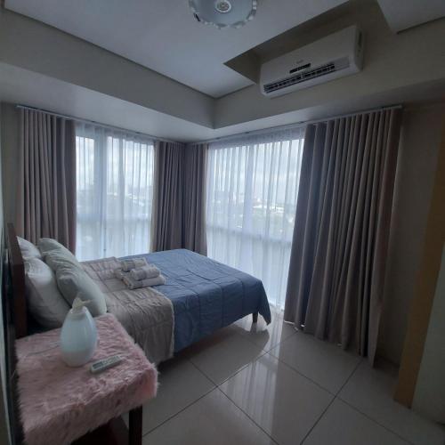 a bedroom with a bed and a large window at De Luxe, Standard and Studio Suites -The Breeze Residences-close to Airport,Mall of Asia, US Embassy in Manila