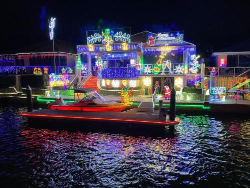 a boat covered in christmas lights on the water at "WATERLILY HOUSE" - Luxury Canal House, Jetty, Dog & Child Friendly - Sleeps 14 in Mandurah