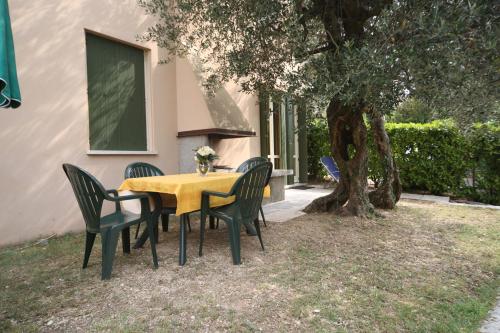 a yellow table and chairs under a tree at Appartamenti Pratone in Garda