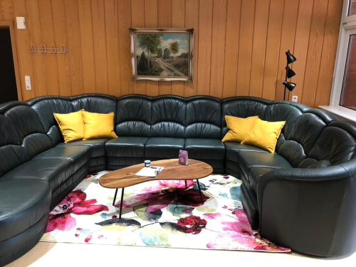a black leather couch with yellow pillows and a table at Heidhof in Bispingen