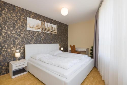 een wit bed in een slaapkamer met een muur bij Vienna Stay Apartments Linzerstrasse in Wenen