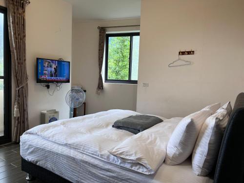 a bedroom with a bed with white sheets and a tv at 溪頭18號 in Lugu