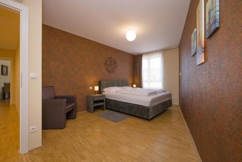 Vienna Stay Apartments Linzerstrasse في فيينا: غرفة نوم بسرير واريكة وكرسي