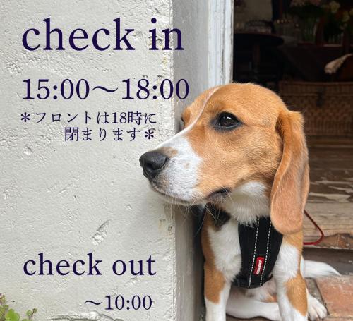 a brown and white dog sitting next to a sign at Kamakurayama Holiday Flat in Kamakura