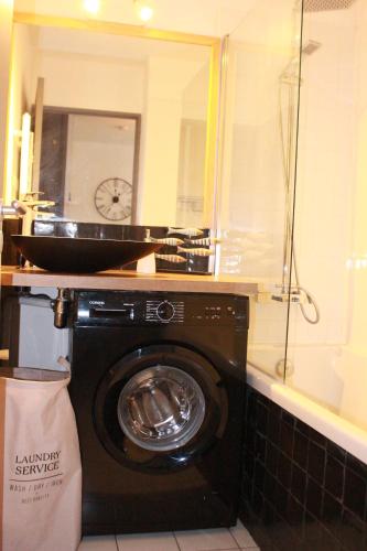 a washing machine in a bathroom with a clock on the wall at Appartement cozy aux Beaux Arts - Casa La Selva in Montpellier
