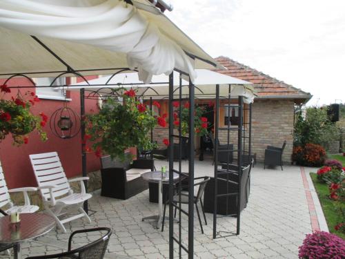 a patio with tables and chairs and an umbrella at Vila Boska Palic in Palić