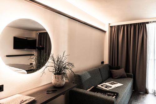 a living room with a couch and a mirror at Hotel Pinei in Ortisei