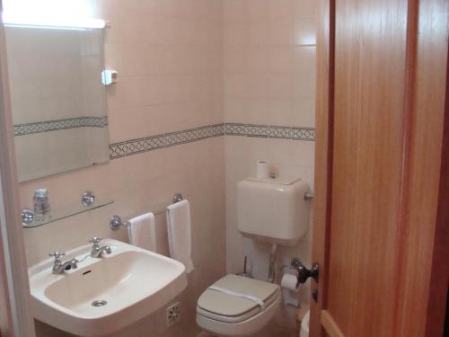 y baño con lavabo, aseo y espejo. en Residencial Elisio, en Paião