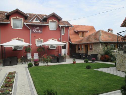 a red house with a green lawn in front of it at Vila Boska Palic in Palić