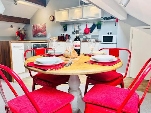 a kitchen with a wooden table and red chairs at Burley Apartment in Burley in Wharfedale