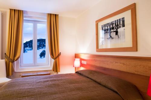 a bedroom with a bed and a large window at Maloja Palace Suites CO2-Neutral in Maloja