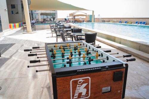 a pool table with a game of chess next to a swimming pool at Luxe Grand Hotel Apartments in Sharjah