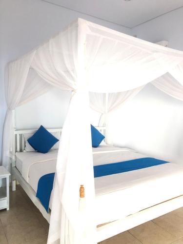 a bedroom with a white canopy bed with blue pillows at Salt Resort & Spa in Amed