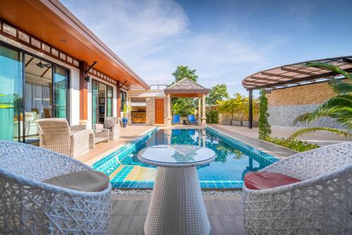 an outdoor patio with a table and chairs next to a swimming pool at Rawayana West Villas & Kids Park, Formerly Rawai VIP Villas in Rawai Beach