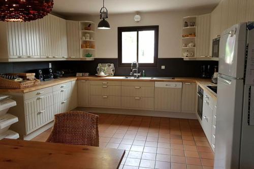 a kitchen with white cabinets and a sink and a window at Le Jardin des Copains in Canet