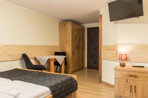 a bedroom with a bed and a table and a television at Leśny Dwór in Murzasichle