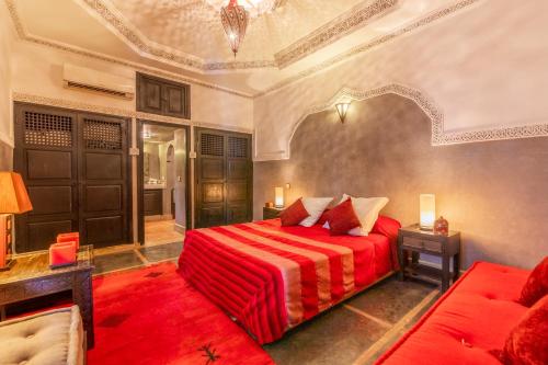 een slaapkamer met een rood bed en een bank bij Riad Espoir, Riad de charme en exclusivité dans la médina de Marrakech in Marrakesh