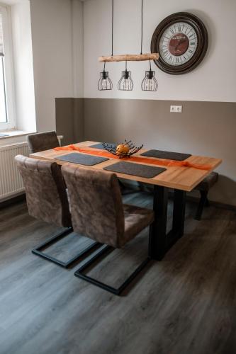 a dining room table with chairs and a clock on the wall at Ferienwohnungen Finkengrund in Büren